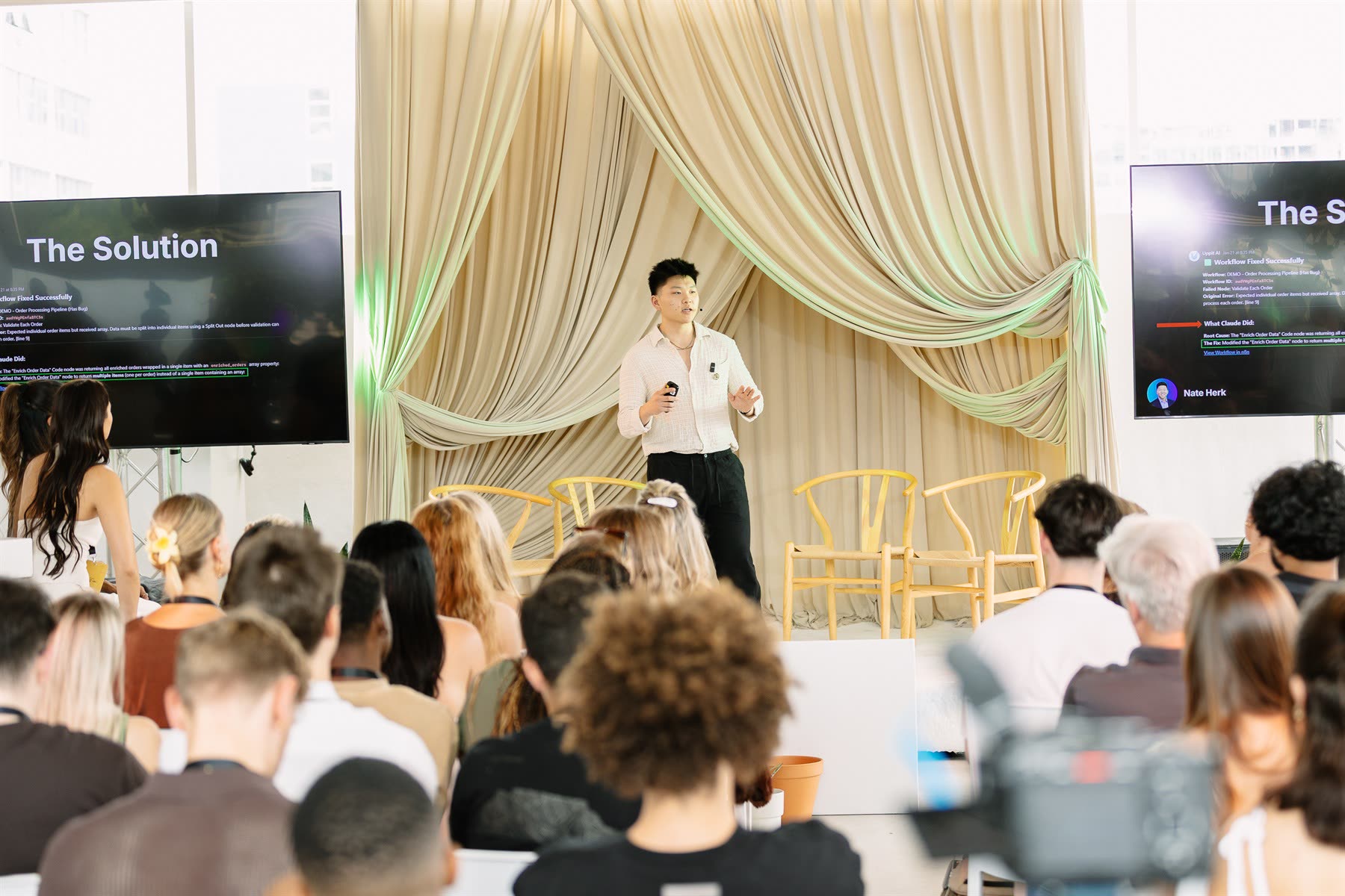 Nate Herk speaking on stage to a seated audience at AfricAI.